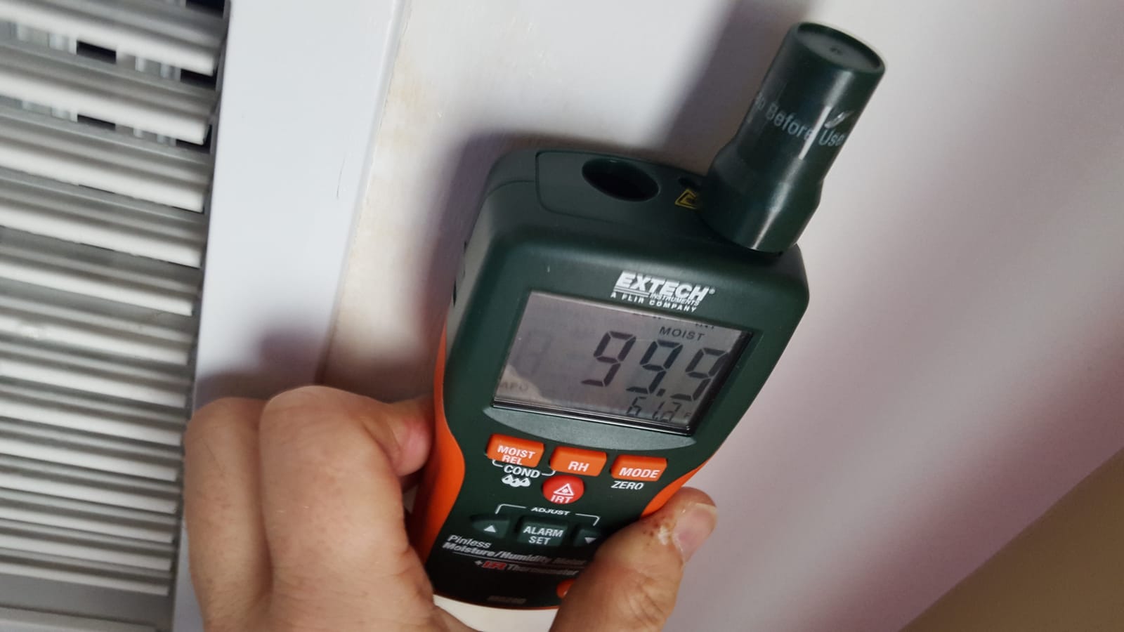 Moisture meter showing 99% reading at HVAC vent in water-damaged home